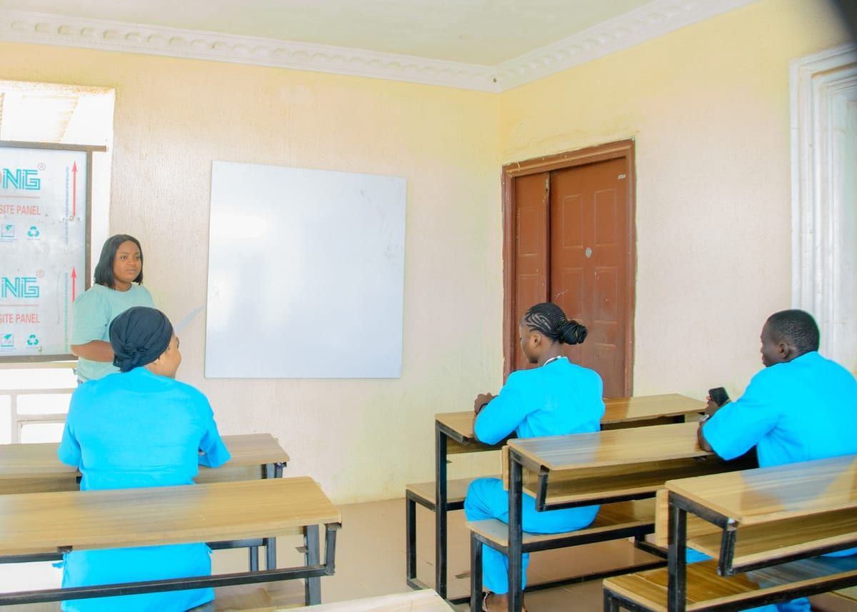 A lecturer teaching a class of students in scrubs at AMB College of Health Technology