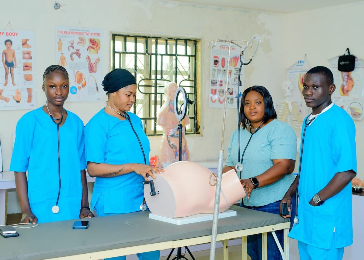An instructor demonstrating on a training manikin to students in scrubs at AMB College of Health Technology