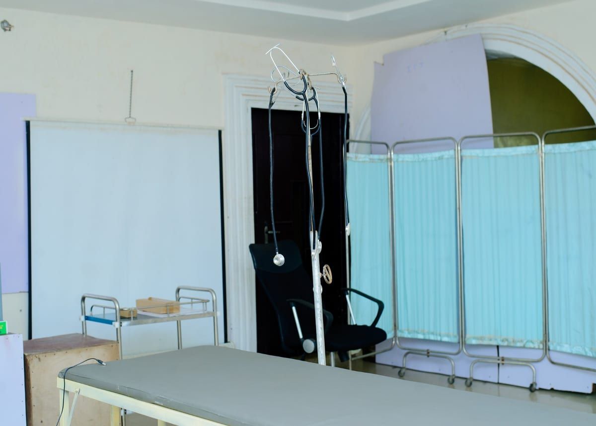 The college clinic, with an examination couch, instrument trolley and ward screen